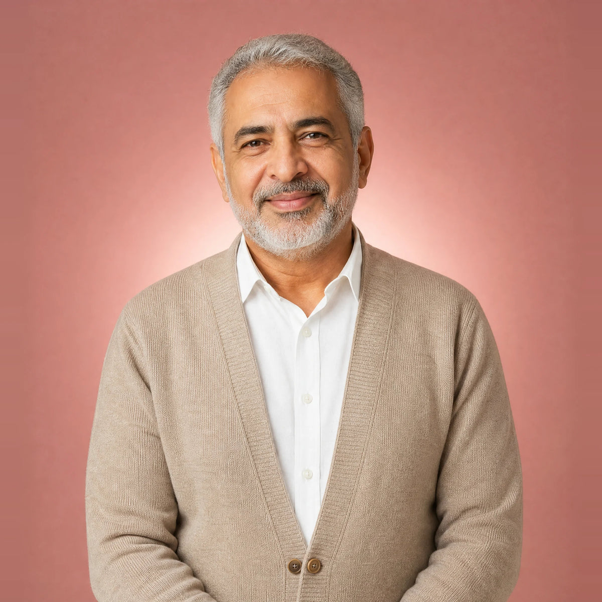 Smiling older man with a grey beard in a beige cardigan