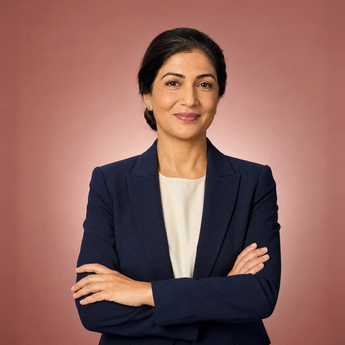 Confident woman in a navy blazer with her arms crossed, smiling
